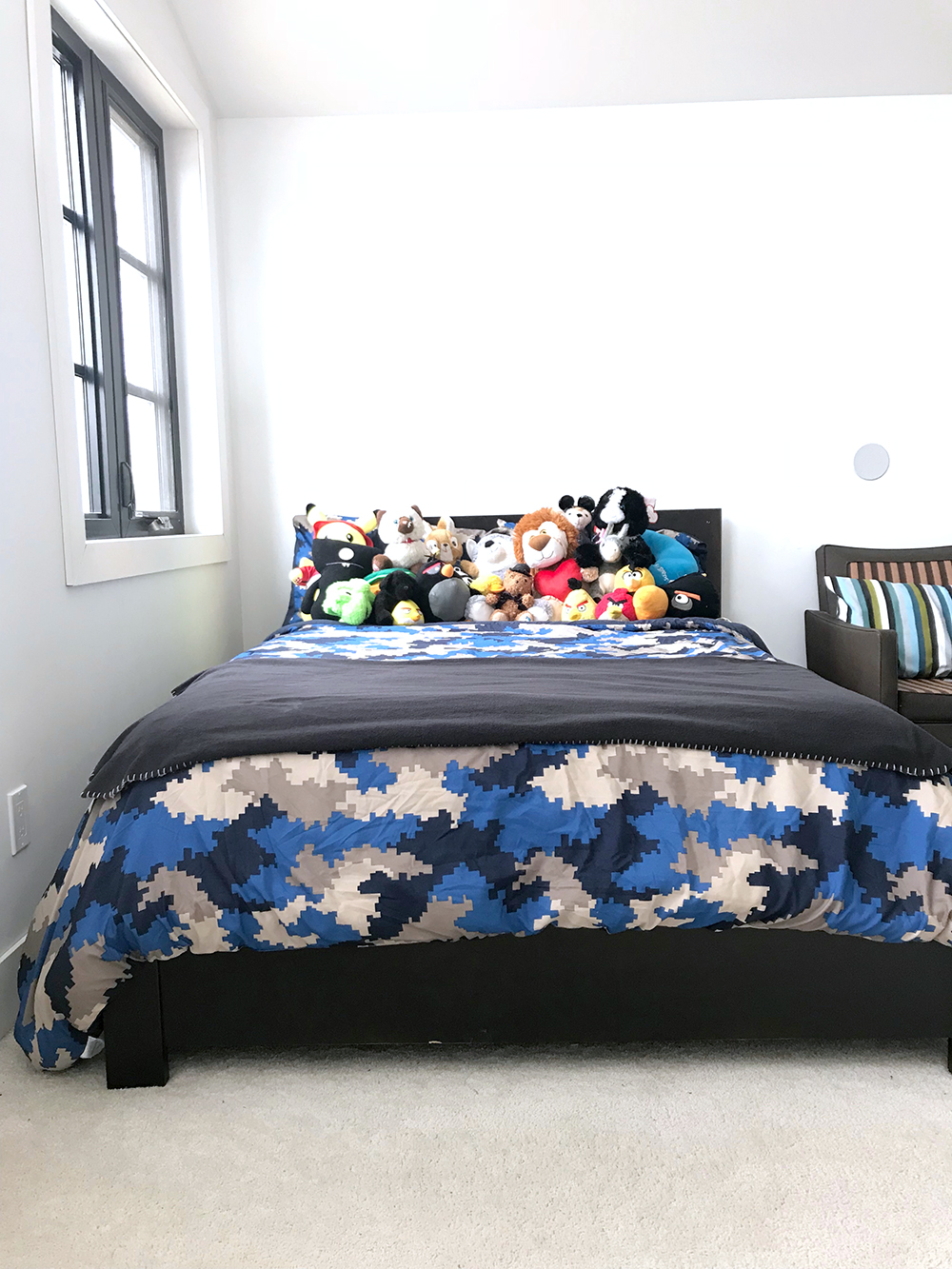Boys bedroom before: a bed full of stuffed animals provides the only colour in the room