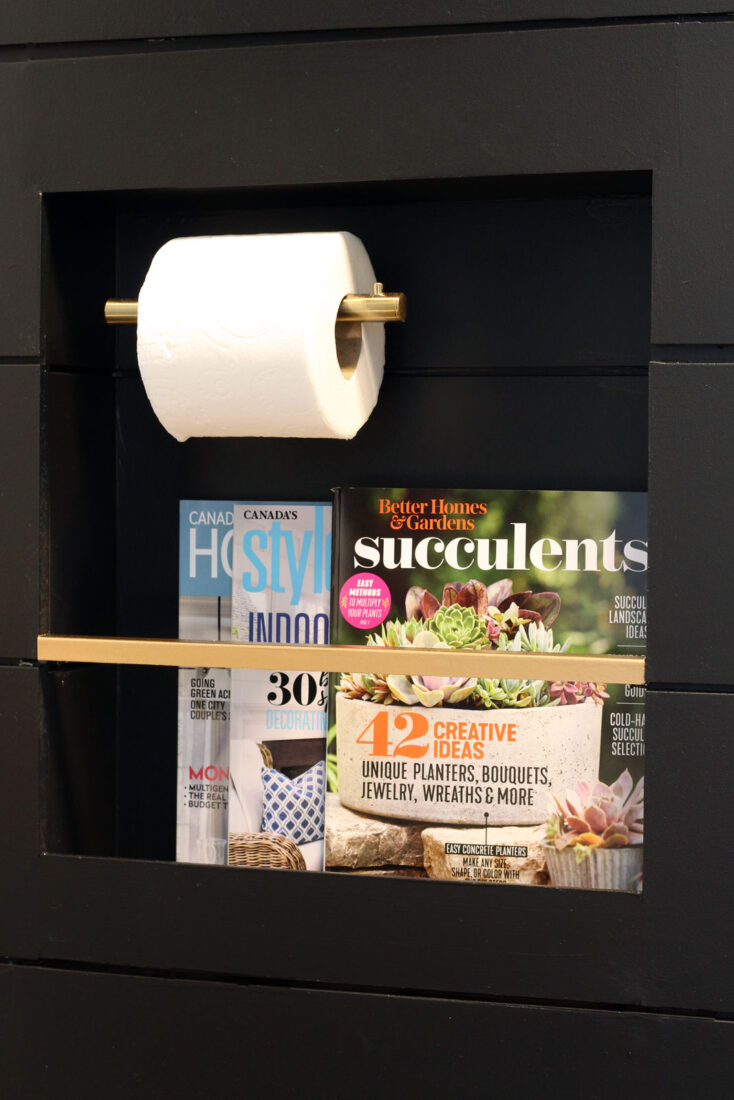 Magazines & toilet paper roll are inset into the shiplap wall in this stylish niche