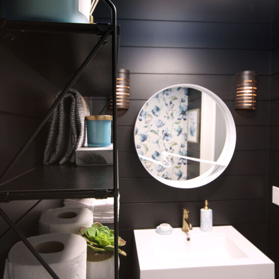 Our sleek and striking powder room reveal features black shiplap walls, a contrasting white vanity, a bold patterned fabric wallpaper feature and gold accents